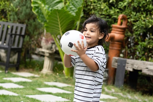 Cute little boy playing soccer with ball outdoors on soccer field photo