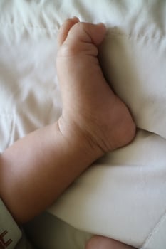 cute feet of a newborn baby on a white mattress photo