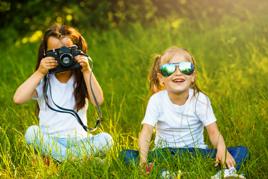 Two children girl female, woman hold a camera take a picture each other with smile photo