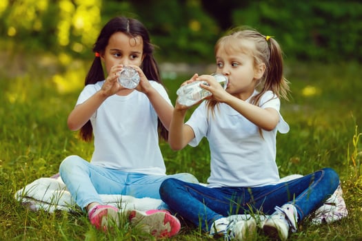 Two little girls are drinking a bottle of water in the park. Concept of purity, ecological and biological product photo
