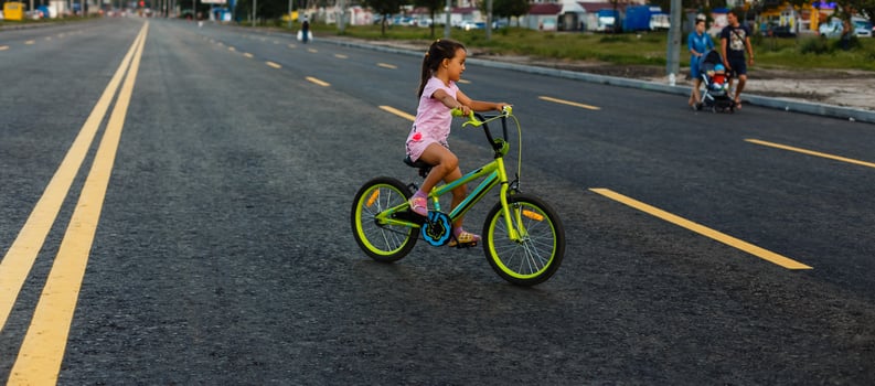 Children learning to drive a bicycle on a driveway outside. Little girls riding bikes on asphalt road in the city wearing helmets as protective gear. photo