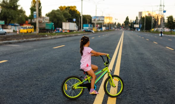 Children learning to drive a bicycle on a driveway outside. Little girls riding bikes on asphalt road in the city wearing helmets as protective gear. photo