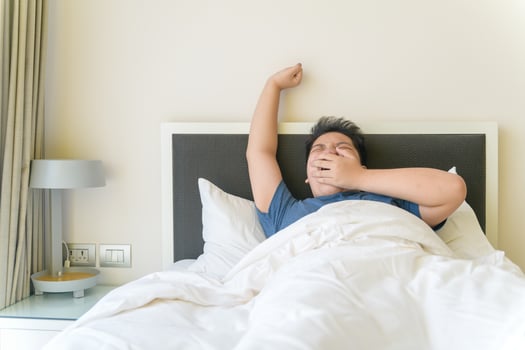Portrait of asian obese boy awaking, wake up on the bed. photo