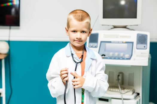 Smiling little boy in medical uniform holding stethoscope and looking at camera photo