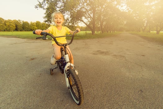 Little girl learns to keep balance while riding a bicycle photo