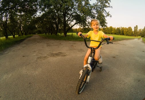Little girl with riding bike at sunset photo