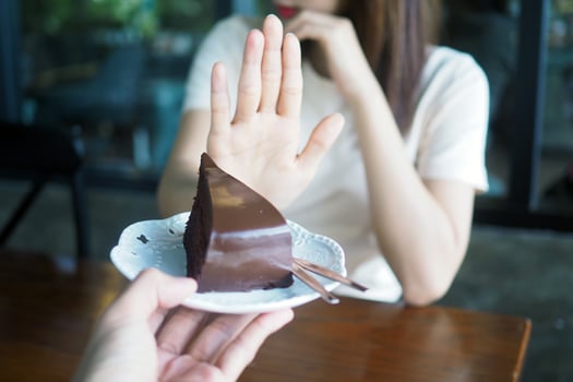 Women refuse to eat trans fat or chocolate cake for weight loss and good health. photo
