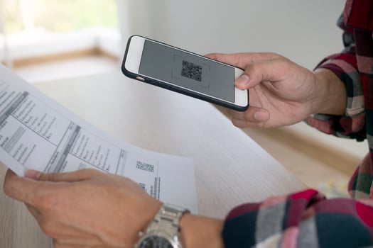 A man uses a smartphone to scan the QR code to pay monthly credit card bills after receiving an invoice sent to home. Online bill payment concept photo