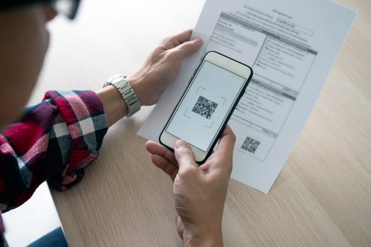A man uses a smartphone to scan the QR code to pay monthly credit card bills after receiving an invoice sent to home. Online bill payment concept photo
