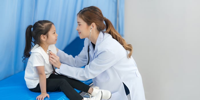 The girl sits on the patient's bed for the doctor. photo
