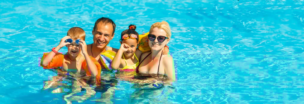 Happy family with two kids having fun in the swimming pool. Summer vacation concept photo