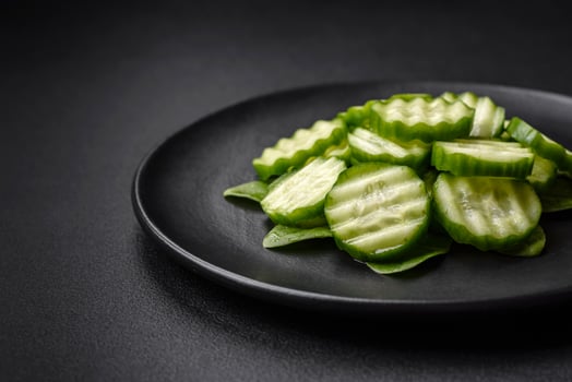 Delicious healthy raw cucumber sliced  on a black ceramic plate photo