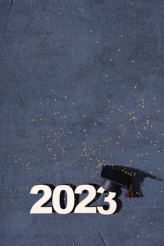 Class of 2023 concept. Wooden number 2023 with graduate statuette on concrete background with tinsel top view photo
