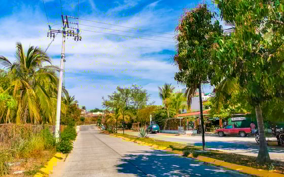 Colorful street with houses palms cars restaurants Puerto Escondido Mexico. photo
