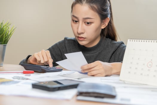 Business financial people, hand of owe asian woman sitting, holding many bills, stressed by calculate expense from receipt, no money to pay, mortgage or loan. Debt, bankruptcy or bankrupt. photo