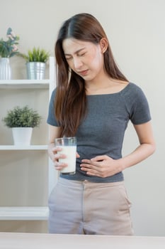 Pain, Allergy asian young woman, girl hand in belly suffer after drink glass of milk, suffer and bad stomach ache. Lactose intolerance and dairy food , health problem concept. photo