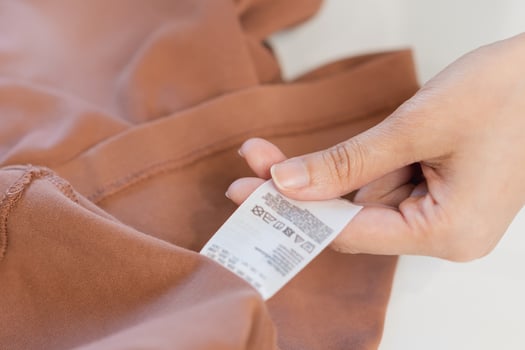 Housewife, asian young woman hand in holding shirt label, tag with instructions, guide before clean clothes, fabric into washing, drying machine, making household working at home. Laundry and maid. photo