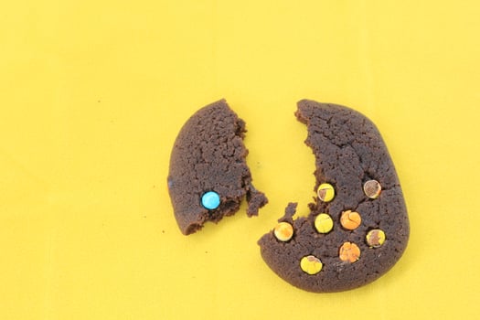hand eaten chocolate chip cookies on yellow background close up photo