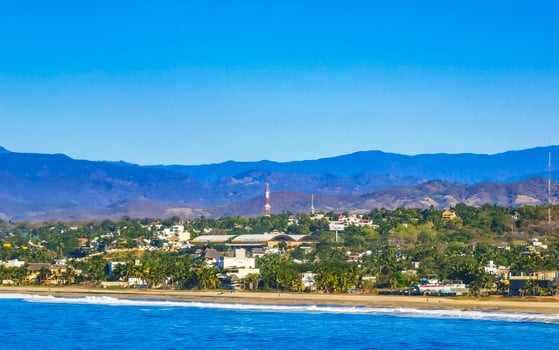 Sun beach cliffs rocks waves palms mountains Puerto Escondido Mexico. photo