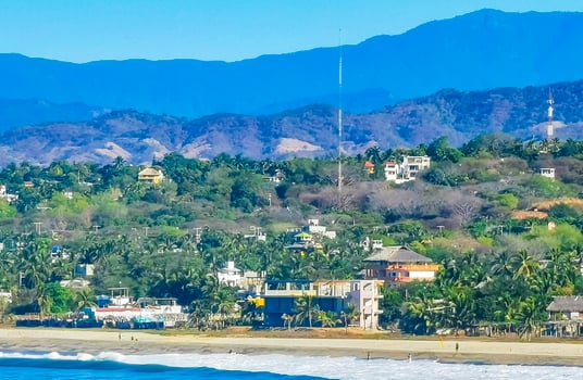 Sun beach cliffs rocks waves palms mountains Puerto Escondido Mexico. photo
