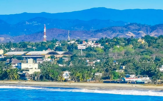 Sun beach cliffs rocks waves palms mountains Puerto Escondido Mexico. photo