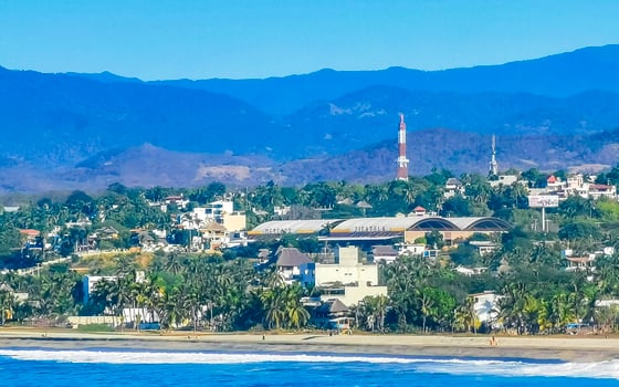 Sun beach cliffs rocks waves palms mountains Puerto Escondido Mexico. photo
