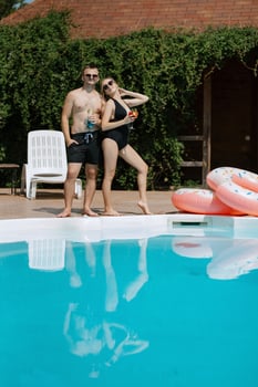 guy and a girl in bathing suits are relaxing, near the blue pool photo
