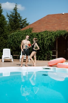 guy and a girl in bathing suits are relaxing, near the blue pool photo
