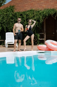 guy and a girl in bathing suits are relaxing, near the blue pool photo