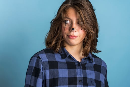 Cute, fashionable, cheeky Caucasian brunette with clown makeup and long hair, dressed in a plaid shirt photo