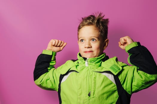 A smiling European boy of five years old demonstrates strength with his hands photo