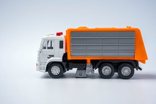 A toy garbage truck with an orange body on a white background. photo