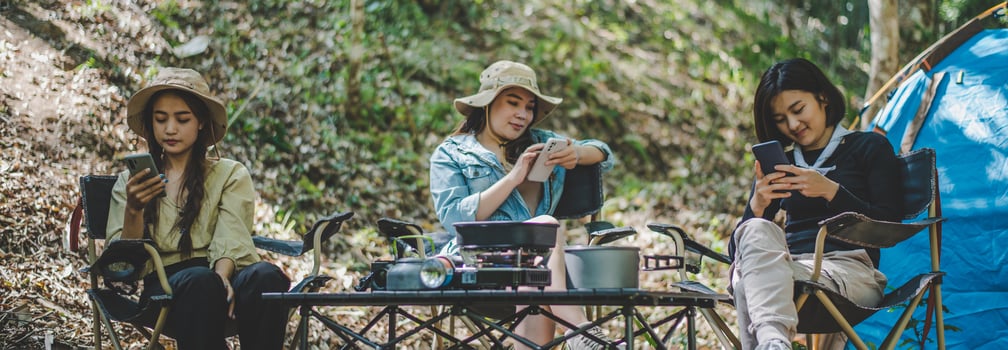 Group of girl friends with smartphone while camping in park photo
