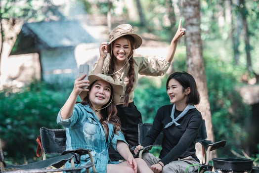 Asian pretty woman and girlfriend use smartphone selfie on camping photo