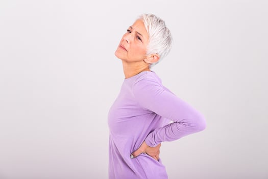 Matur Woman suffering from lower back pain. Mature woman resting with back pain. Female lower back pain. Senior woman injury suffering from backache photo
