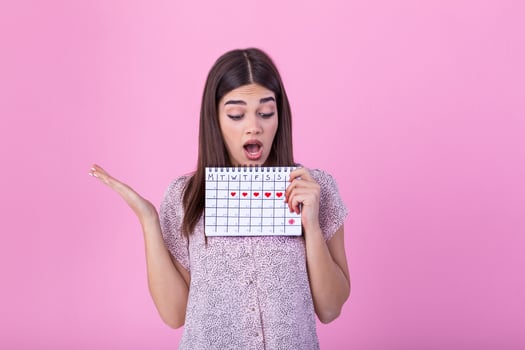 Young caucasian woman holding menstruation calendar over isolated background scared in shock with a surprise face, afraid and excited with fear expression photo