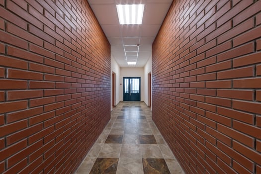 white empty long corridor with red brick walls and doors in interior of modern apartments or office photo