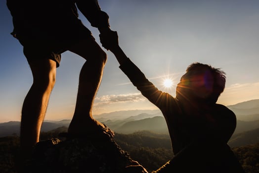 Silhouette of hiker helping each other hike up a mountain at sunset. People helping and, team work concept. photo