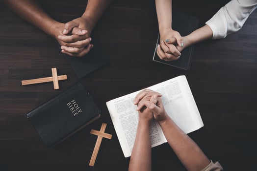 Small groups of Christians hold hands and pray together around a wooden table with bible pages and crosses. bible study group Learning religious concepts in the Bible. Worship God. photo