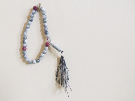 selective focus on prayer beads hanging on white background wall with copy space photo