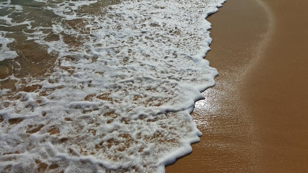 Sea water covers the sandy beach. Wet sand. photo