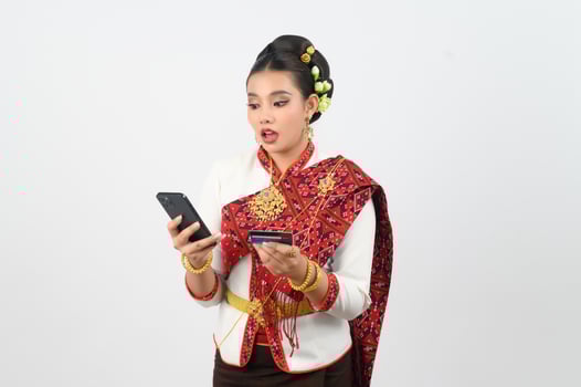 Portrait of Beautiful Thai Woman in Traditional Clothing Posing with smartphone and credit card photo