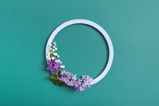 Spring composition. Lily of the valley and lilac flowers with round frame copy space. Summer, spring floral concept photo