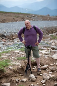 A man is filming a cable car in the mountains with a video camera. A tourist writes a YouTube blog while traveling. photo