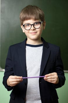 Portrait of a schoolboy at the blackboard. The boy in the classroom is looking at the camera. photo