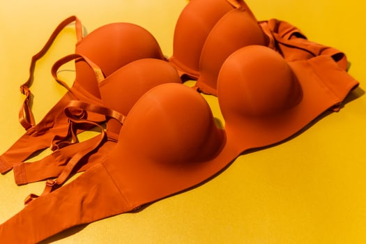 Set of orange color bra on yellow background, closeup. photo