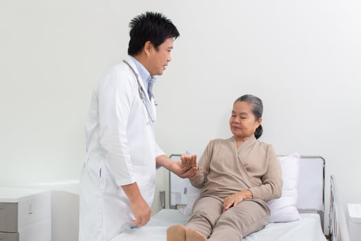 Asian male doctor explaining medicine to elderly female patient in hospital. photo