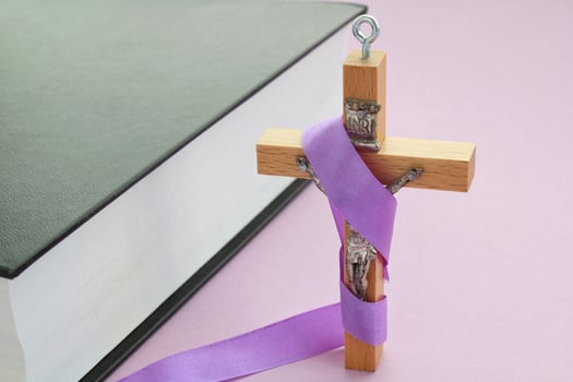 Christian religious wooden cross crucifix with violet ribbon and bible book on purple background. Catholic religion symbol. Good Friday, Lent Season, Palm Sunday, Ash Wednesday and Holy Week concept photo