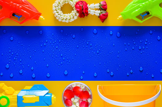 Thailand songkran festival background with water gun, garland , scented water and bucket put on yellow and wet blue background. photo
