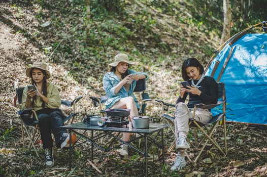 Group of girl friends with smartphone while camping in park photo